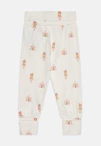 Pantalons en coton crème avec un imprimé répétitif sur le thème du cirque représentant des lions et des tentes, avec des poignets et une taille élastiques pour plus de confort.