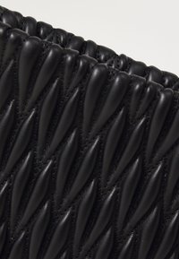 Black leather handbag with a quilted texture featuring raised, pointed patterns. Soft finish with visible stitching details along edges.