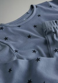 Grijze katoenen shirt met korte mouwen, voorzien van een patroon van zwarte sterren. Zachte textuur en klassiek ronde halsontwerp.