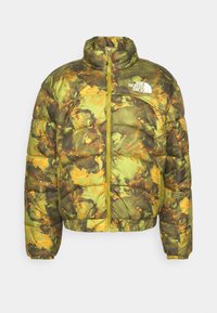 Prošívaná bunda ve vzoru zelené, žluté a hnědé kamufláže. Má zip na přední straně, žebrované manžety a logo na hrudi.