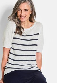 Weißer Strickpullover mit kurzen Ärmeln und navyblauen horizontalen Streifen. Leichter Stoff, weiter Ausschnitt und gerippte Saumdetails.