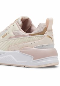 Sneakers Puma w jasnoróżowym kolorze z białymi akcentami. Zawierają teksturowane panele, materiał siatkowy oraz wyściółkę kołnierza dla komfortu.