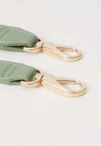 Bracelet en cuir vert avec quincaillerie dorée et détails de couture, comportant deux fermoirs portant l'inscription "VALENTINO".