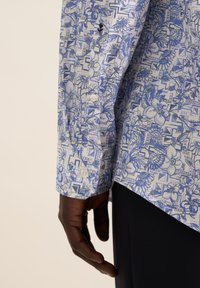 Camicia a maniche lunghe blu e bianca, con un motivo a fiori e geometrici, caratterizzata da polsini con bottoni e una texture di tessuto liscia.
