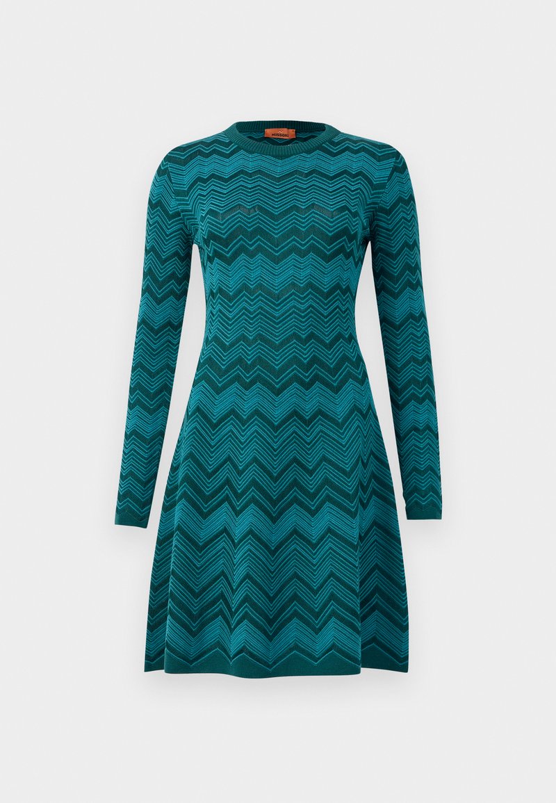 Robe en tricot teal avec un motif en chevrons, dotée de manches longues et d'un col rond. Elle a un corsage ajusté et une jupe évasée.