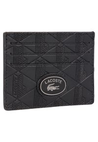 Porte-cartes noir en matériau synthétique texturé, présentant un motif géométrique et un logo ovale Lacoste en métal argenté.