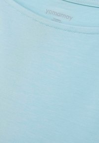 Hellblaues Kurzarmhemd mit glatter Textur, ausgestattet mit einem Rundhalsausschnitt und dem dezent in Silber gedruckten "yamamay"-Logo.