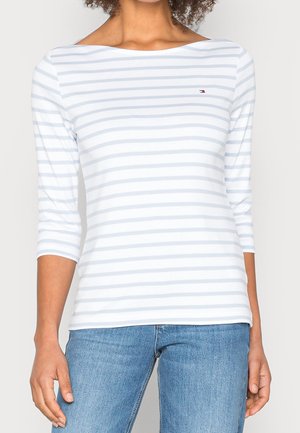 Langärmliges Top mit Bootsausschnitt in Weiß mit hellblauen horizontalen Streifen, aus weichem Material, mit einem kleinen Logo auf der Brust.