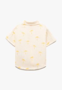 Crème-kleurig T-shirt met korte mouwen, met een geel palmbomenpatroon en een kleine kraag, van achteren weergegeven tegen een witte achtergrond.