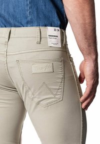 Beige katoenen broek met een reguliere rechte pasvorm, voorzien van een achterzak met geborduurd 'Wrangler' logo en een label met maat 32/34.