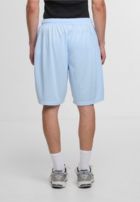 Lyseblå atletikshorts lavet af åndbart stof, med elastisk talje og en glat overflade. Længden når midt på låret.