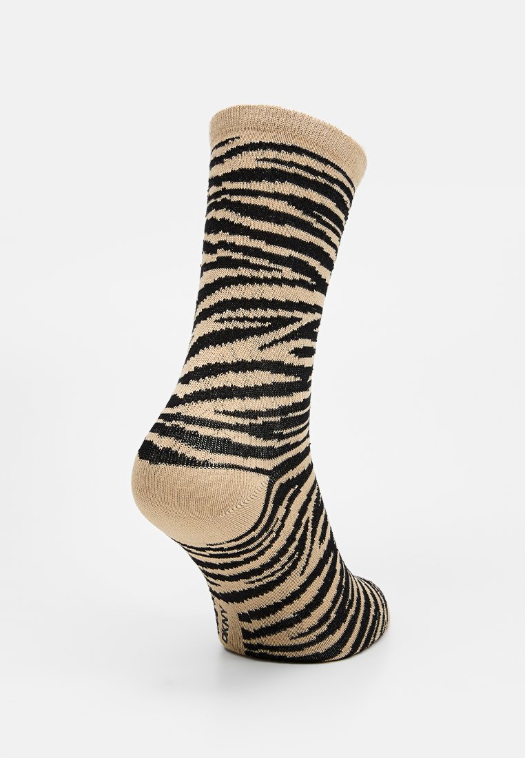 Calcetines beige con un audaz patrón de rayas de cebra negras. El diseño se extiende de manera fluida sobre el talón y el área del tobillo, con una textura suave.