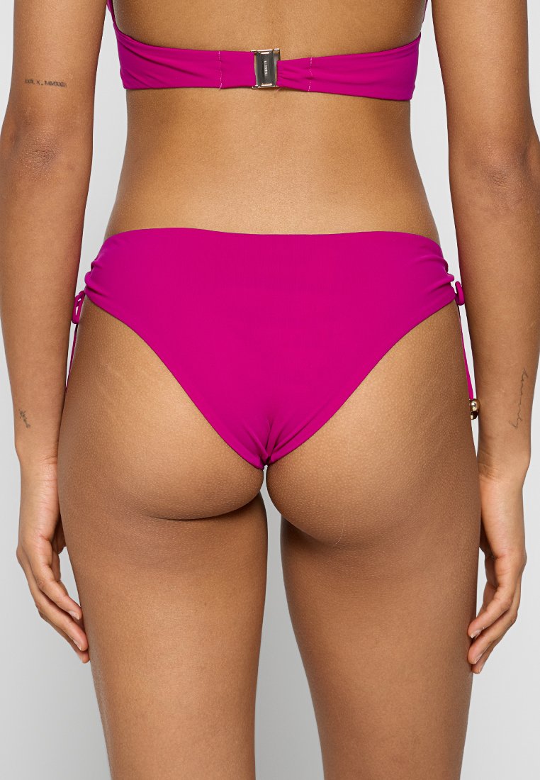 Magenta-bikini-alaosa aina zana na zana; ya laini na ya kufunika kidogo, ikiwa na mapambo ya metal kwenye zana.