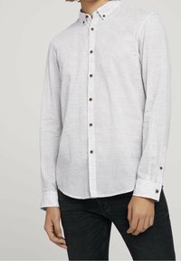 Koszula z długim rękawem, zapinana na guziki, w kolorze białym w czarne paski, z kołnierzykiem i brązowymi guzikami, wykonana z teksturowanej tkaniny.