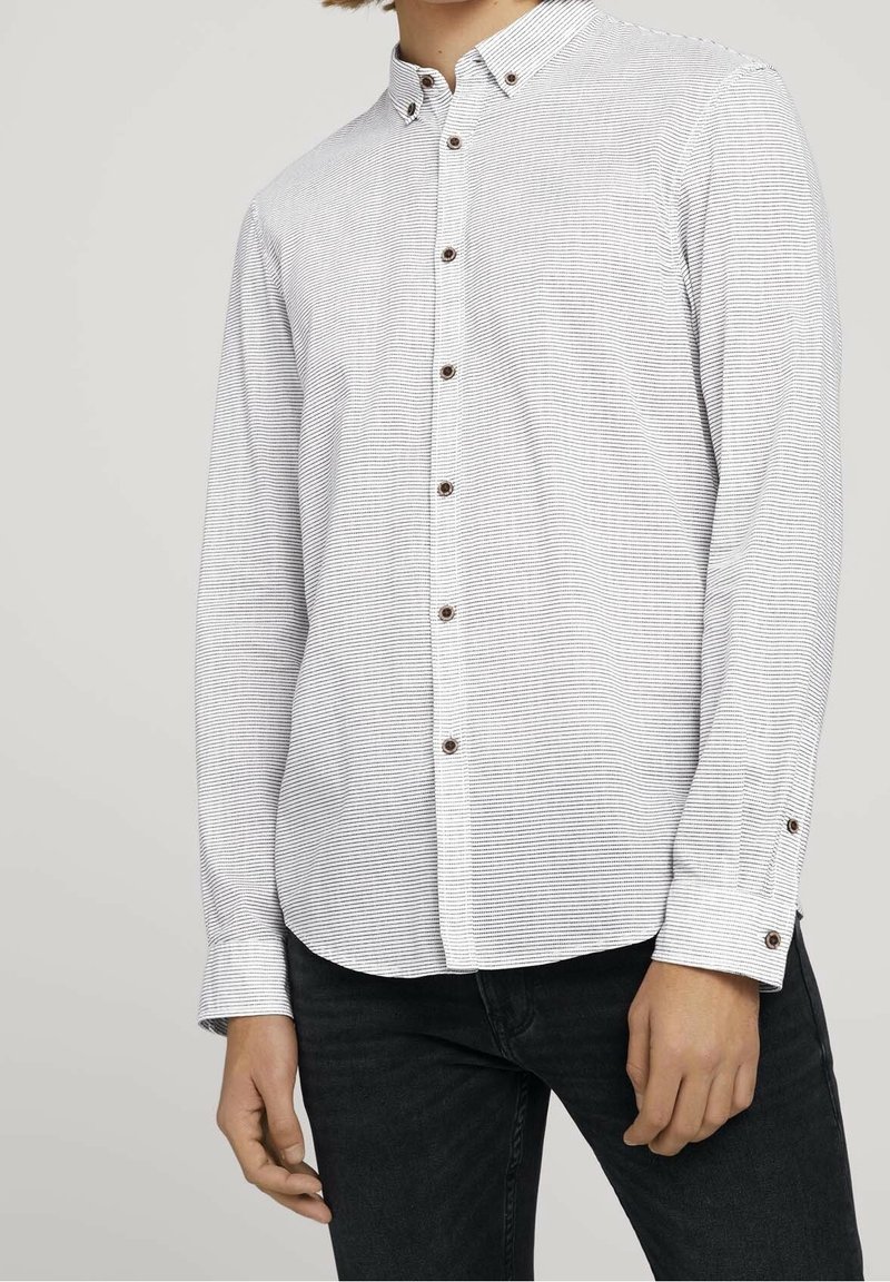 Koszula z długim rękawem, zapinana na guziki, w kolorze białym w czarne paski, z kołnierzykiem i brązowymi guzikami, wykonana z teksturowanej tkaniny.