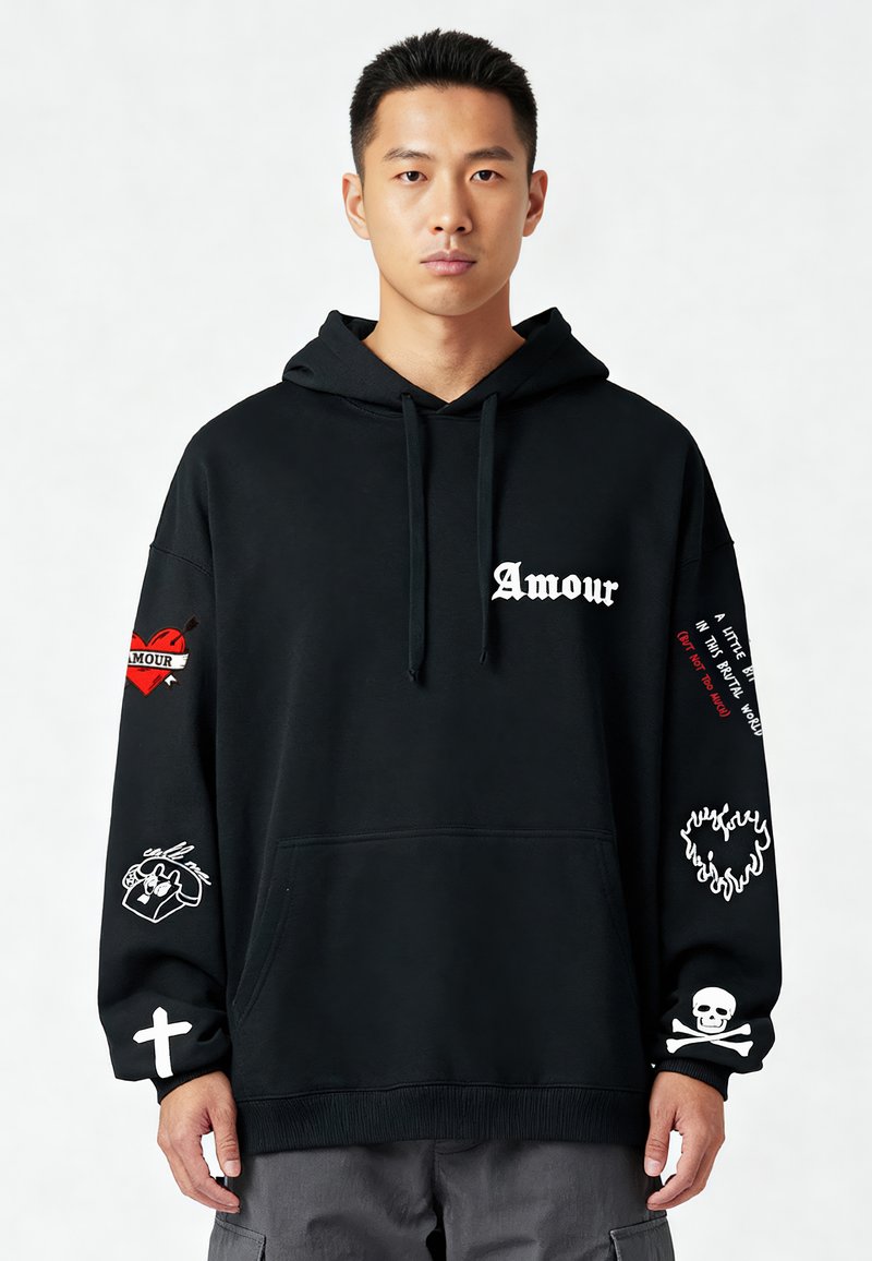 Hoodie noir avec une poche avant. Décoré de textes blancs et rouges, ainsi que de graphiques de cœurs et de skulls sur les manches. Matériau doux, coupe décontractée.