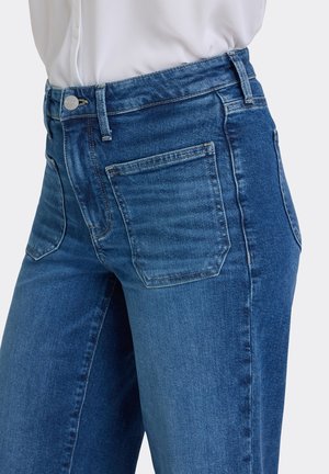 Blå denimjeans med en mellemhøj pasform, der har to baglommer og en glat tekstur. Metallukning med knap og bæltestropper i taljen.
