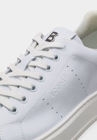 Baskets en cuir blanc avec lacets blancs, embossées du mot « BOGNER » sur le côté, et logo noir « B » sur la languette.