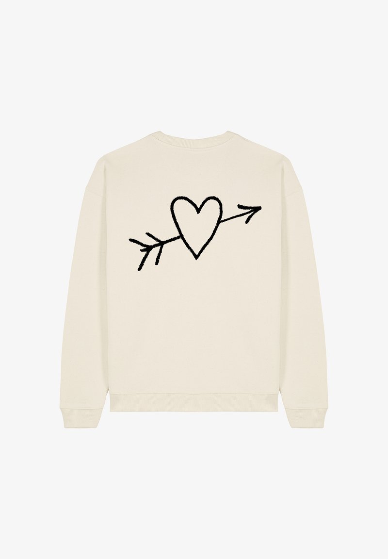 Krém színű pulóver fekete szív és nyíl mintával hímzéssel a hátsó részen. Puha textúra, bordás mandzsettákkal és alján.