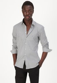 Gestreiftes Hemd in Schwarz und Weiß, mit langen Ärmeln, Kragen und einer Brusttasche, entworfen in schlanker Passform und glatter Textur.