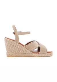 Beige espadrille wedge sandaal met een gestructureerde bovenkant, kruisspanning ontwerp en decoratieve kraaltjes. Kenmerkt een geweven jute platform en enkelband.