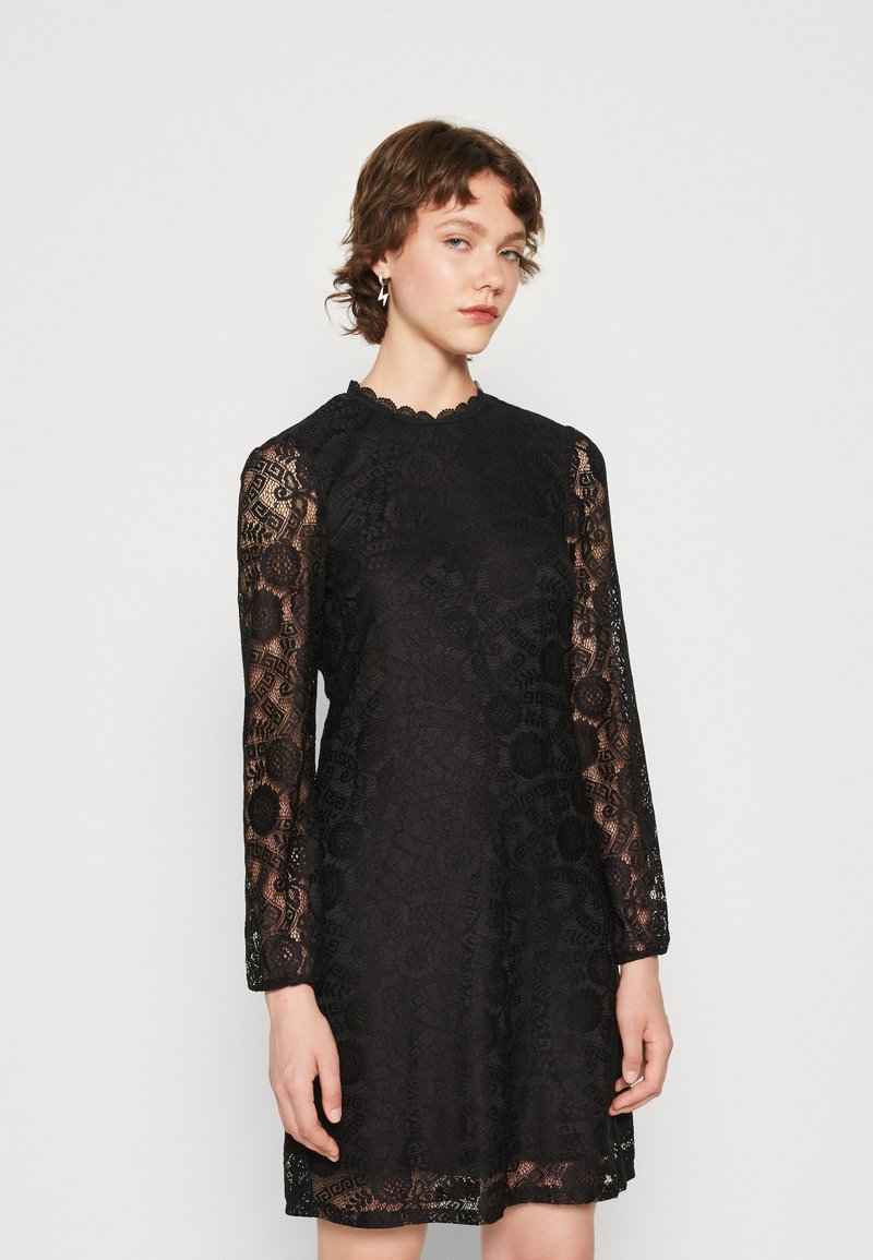 Black lace dress with long sleeves, scalloped neckline, intricate floral patterns, and a slightly flared hem. Textured design throughout.