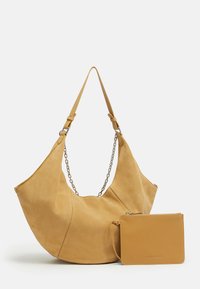 Gelbe Hobo-Tasche aus Wildleder mit Kettenakzent und abnehmbarer passender Tasche. Weiche Textur, geschwungene Form und dezente Nahtdetails.