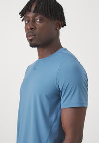 Αθλητική μπλούζα κοντομάνικη σε ανοιχτό μπλε, κατασκευασμένη από μαλακό ύφασμα. Διαθέτει στρογγυλή λαιμόκοψη και διακριτική επωνυμία στο στήθος.