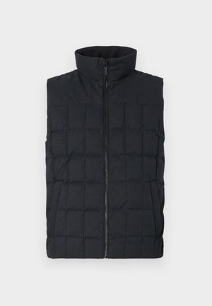 Chaleco acolchado negro tipo puffer con cuello alto y cremallera frontal, con costuras cuadradas y bolsillos laterales. Textura de tela suave.