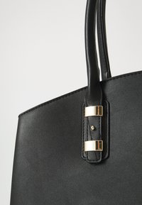 Black leather handbag with smooth texture, featuring gold hardware accents and sturdy handles. Simple design with no visible patterns.