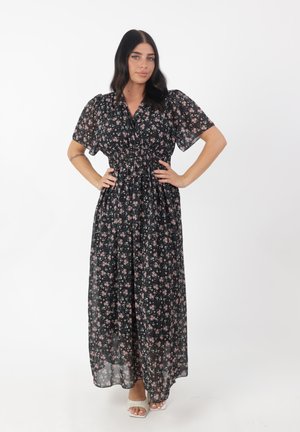 Abito maxi in tessuto nero trasparente con piccole stampe floreali rosa. Presenta maniche corte a sbuffo e una vita elasticizzata per un design fluido.