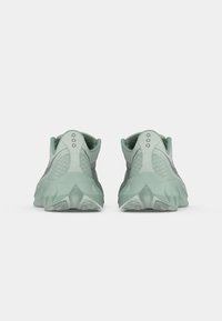 Pair of green athletic shoes shown from the back with textured soles and mesh fabric details, set against a plain white background.