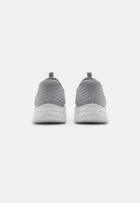 Baskets de sport grises avec un dessus en maille texturée, une semelle blanche mouchetée et une languette au dos pour un enfilage facile. Conception douce et légère.