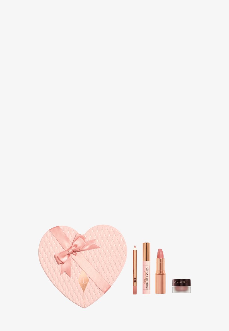 Herzförmige, pinkfarbene, gepolsterte Geschenkbox mit Satinband und vier pinktönigen Make-up-Produkten, darunter Lippenstift, Mascara, Lipliner und Creme.