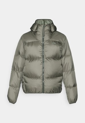 Olíva zöld színű pufi dzseki, magas gallérral, cipzáras elülső résszel és rugalmas mandzsettákkal. Könnyen steppelt kialakítás, diszkrét márkajelzéssel.