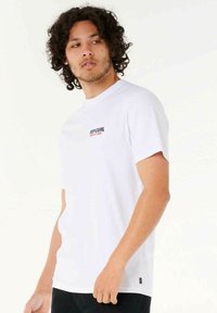 Weißes T-Shirt mit kurzen Ärmeln aus Baumwolle; verfügt über ein schwarzes und rotes "RIP CURL"-Logo auf der Brust; gerader Schnitt mit Rundhalsausschnitt.