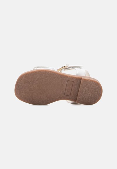 Λευκό παιδικό σανδάλι με υφή καφέ σόλας και χρυσή αγκράφα, εμφανίζεται από κάτω σε λευκό φόντο.