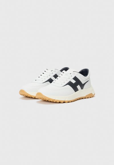 Baskets blanches avec des accents noirs, dessus en cuir texturé, bout rond et semelle en caoutchouc. Design à lacets avec un soutien rembourré à la cheville.