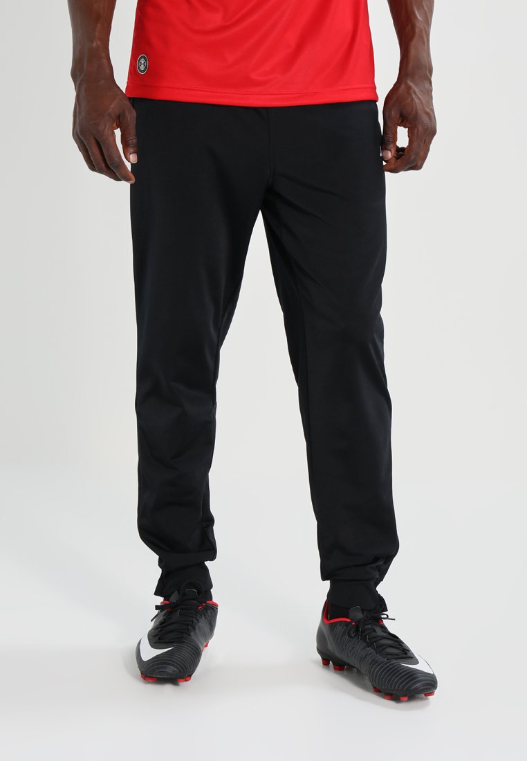 Pantaloni sportivi neri con vestibilità affusolata e polsini elasticizzati, abbinati a scarpe da calcio nere con dettagli rossi e logo Swoosh bianco.