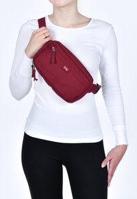 Borsa a tracolla marrone realizzata in tessuto resistente, con due scomparti con zip, tracolla regolabile e un piccolo'etichetta con logo.