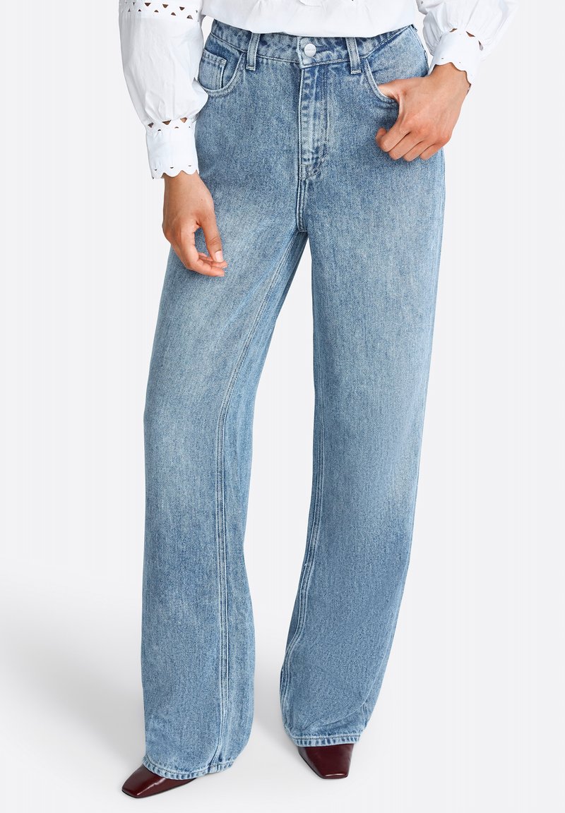 Jeans in denim blu a gamba larga con vita alta, dotati di tasche frontali e un lavaggio sbiadito. Il materiale è spesso con cuciture ben visibili.