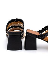 Sandalias de tacón negro con tiras trenzadas en negro y marrón claro, un tacón cuadrado y una plantilla suave en beige.