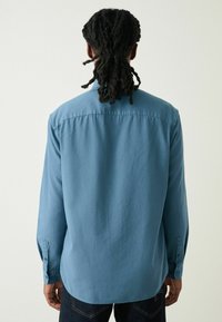 Lichtblauwe lange mouwen overhemd van gestructureerde stof, met een standaardkraag en knoopmanchetten, met een relaxte pasvorm en een gebogen zoom.