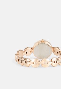 Rose gold watch with a round case, circular link bracelet, and a minimalist dial. Features prominent brand engraving and smooth texture.