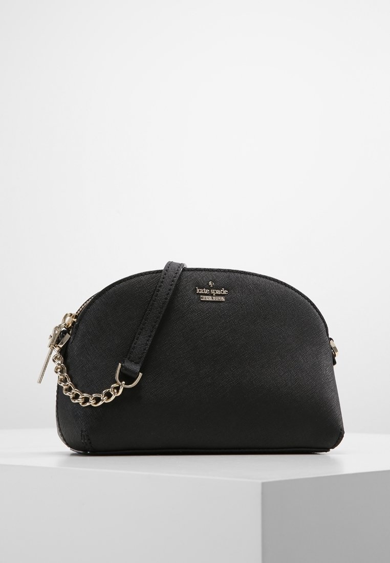 Černá taška přes rameno s zakřiveným tvarem, vyrobená z texturovaného materiálu. Obsahuje zlaté kovové prvky a řetízkový zdobný prvek na popruhu.
