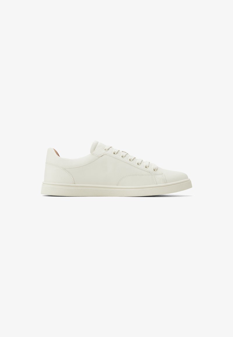 Zapatillas de cuero blancas con diseño bajo, punta redonda, cordones en la parte delantera y suela de goma. Textura suave y estilo minimalista.