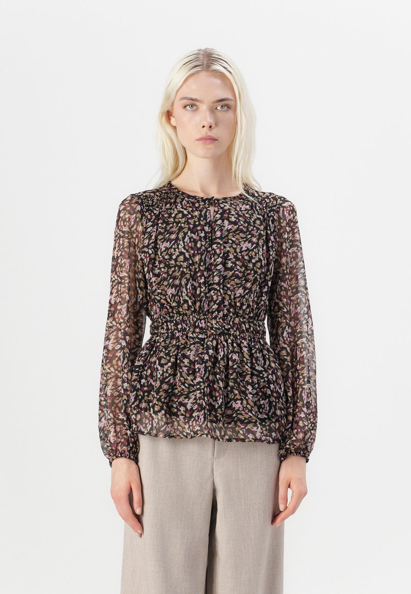 Svart blommig blus med långa ärmar, genomskinligt tyg, sammanknuten midja och ömtåliga mönster i rosa, grönt och beige. Matchad med ljusgrå byxor.