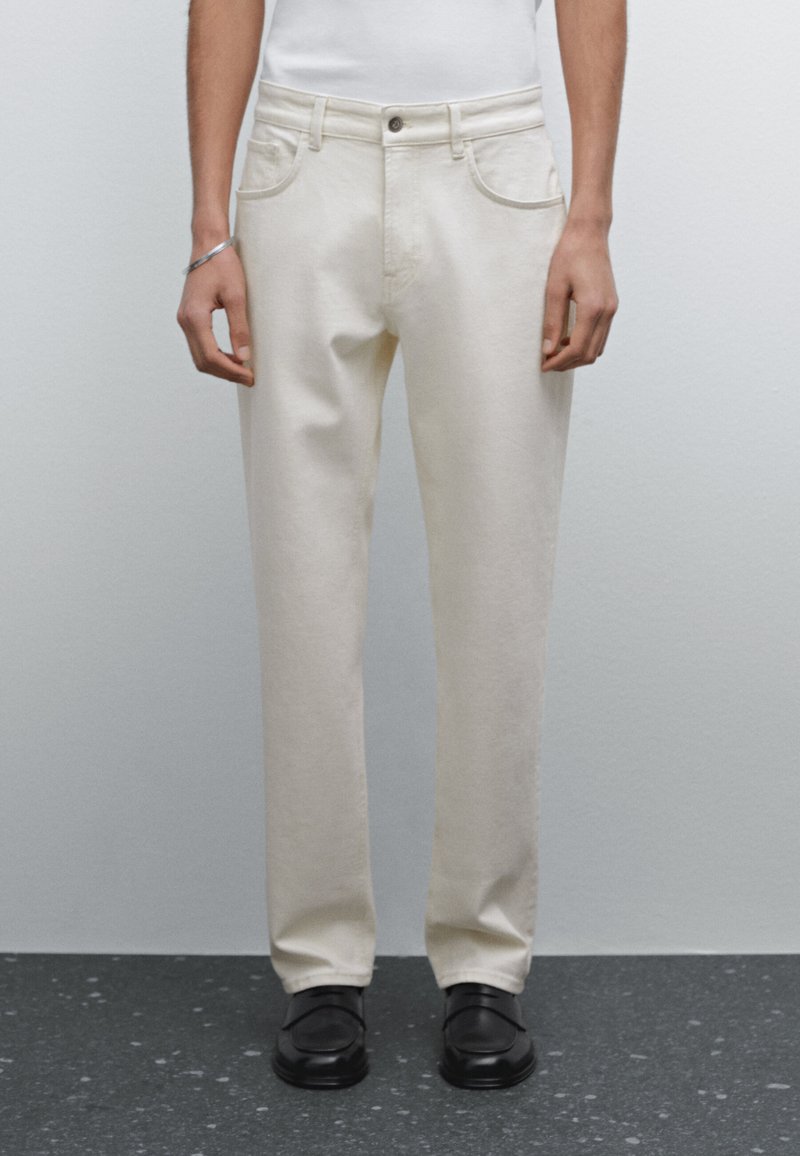 Pantaloni beige a gamba dritta realizzati in tessuto misto cotone, con tasche frontali, passanti per cintura e chiusura con un'unica bottone.
