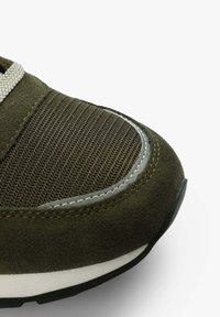 Grüne Wildleder-Sneaker mit strukturiertem Mesh-Obermaterial, grauen Akzenten und weißer Zwischensohle. Verfügt über eine abgerundete Zehenpartie und kontrastierende Stichdetails.