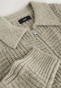 Jasnoszary wełniany sweter kardigan z kołnierzem, srebrnym zamkiem błyskawicznym i ściągaczami, z czarną metką z napisem "NEXT".